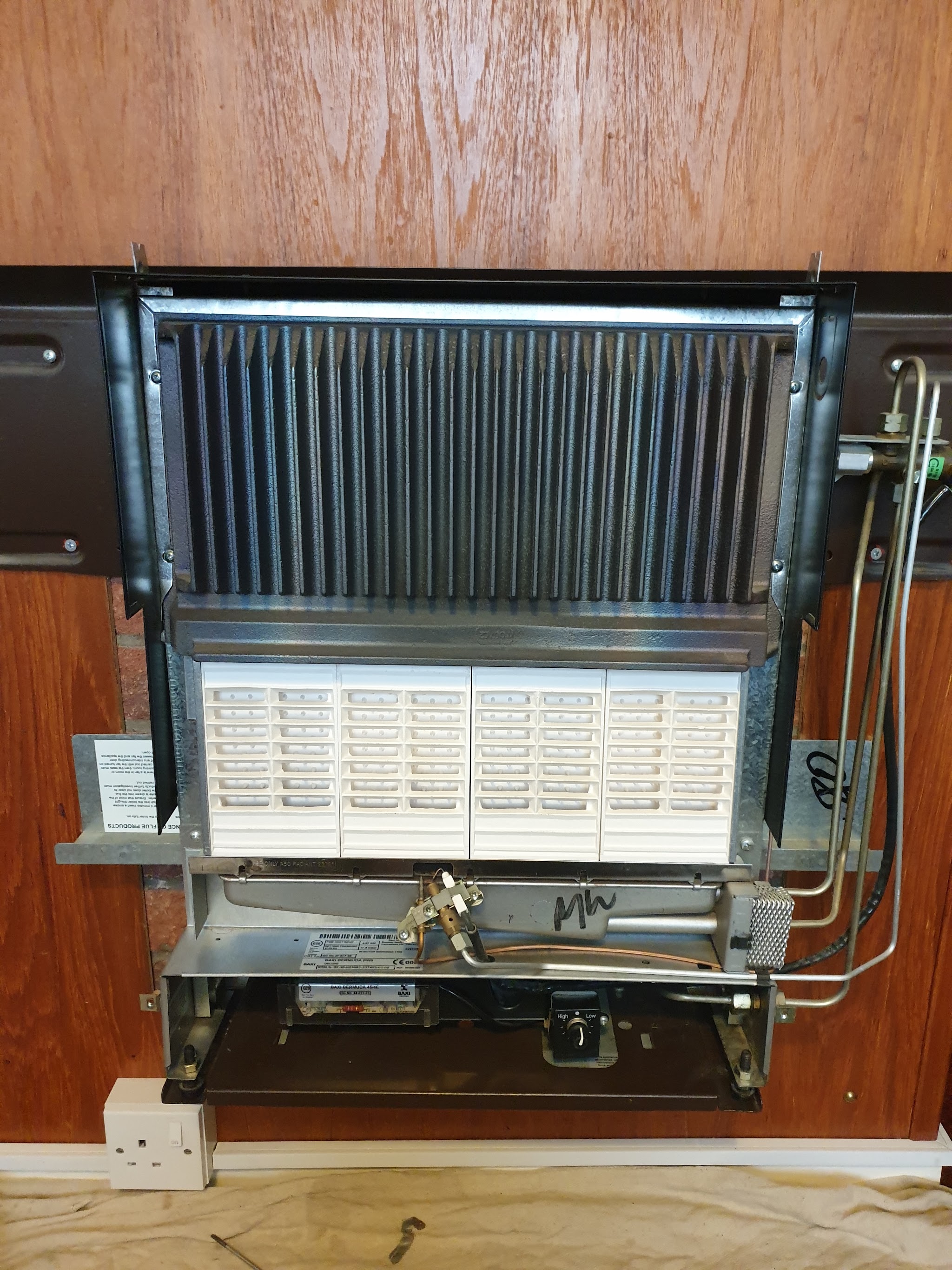 An old gas fire with its front removed, showing the heat exchanger