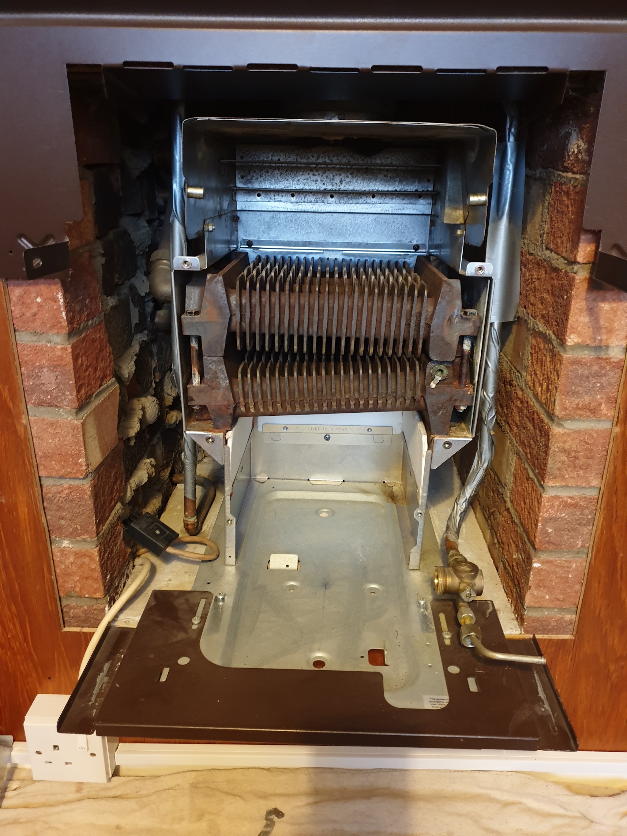 An old back boiler opened up inside a brick fireplace recess